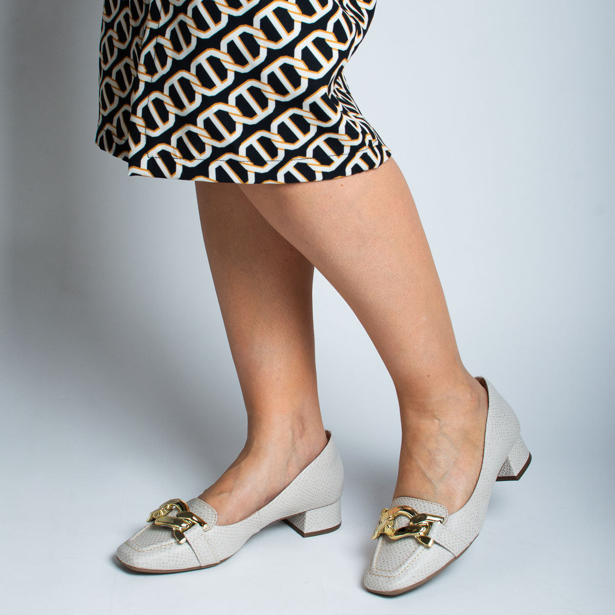 Woman wearing scale off-white Coentro pumps with patterned skirt - lifestyle view