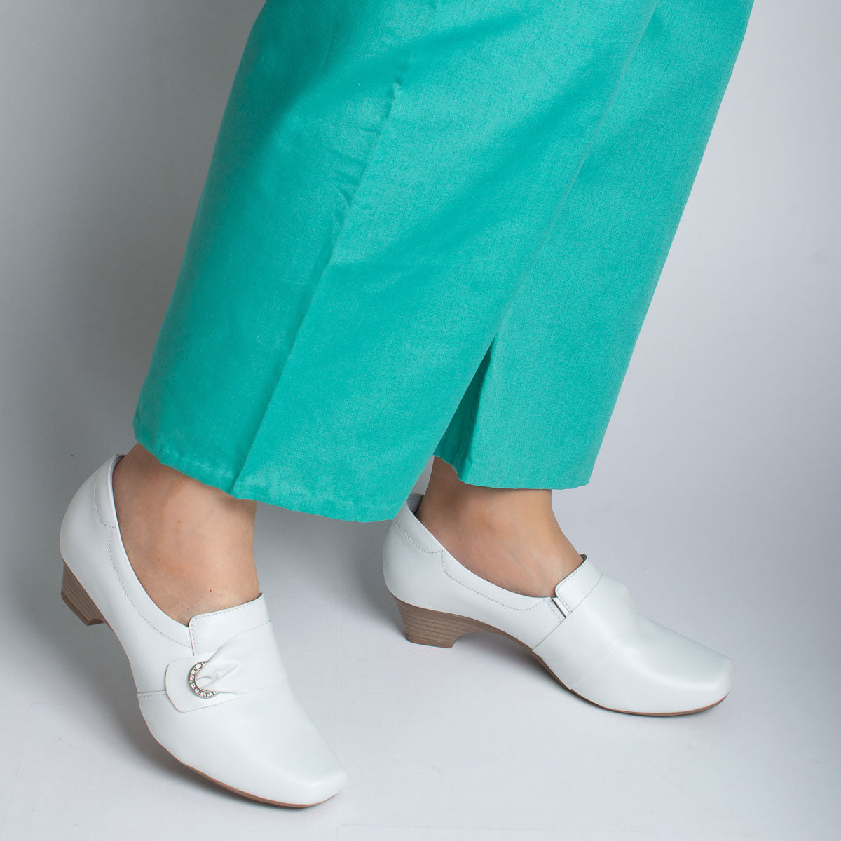 Woman wearing vegetal off-white Andiroba shoes with teal scrubs - lifestyle view