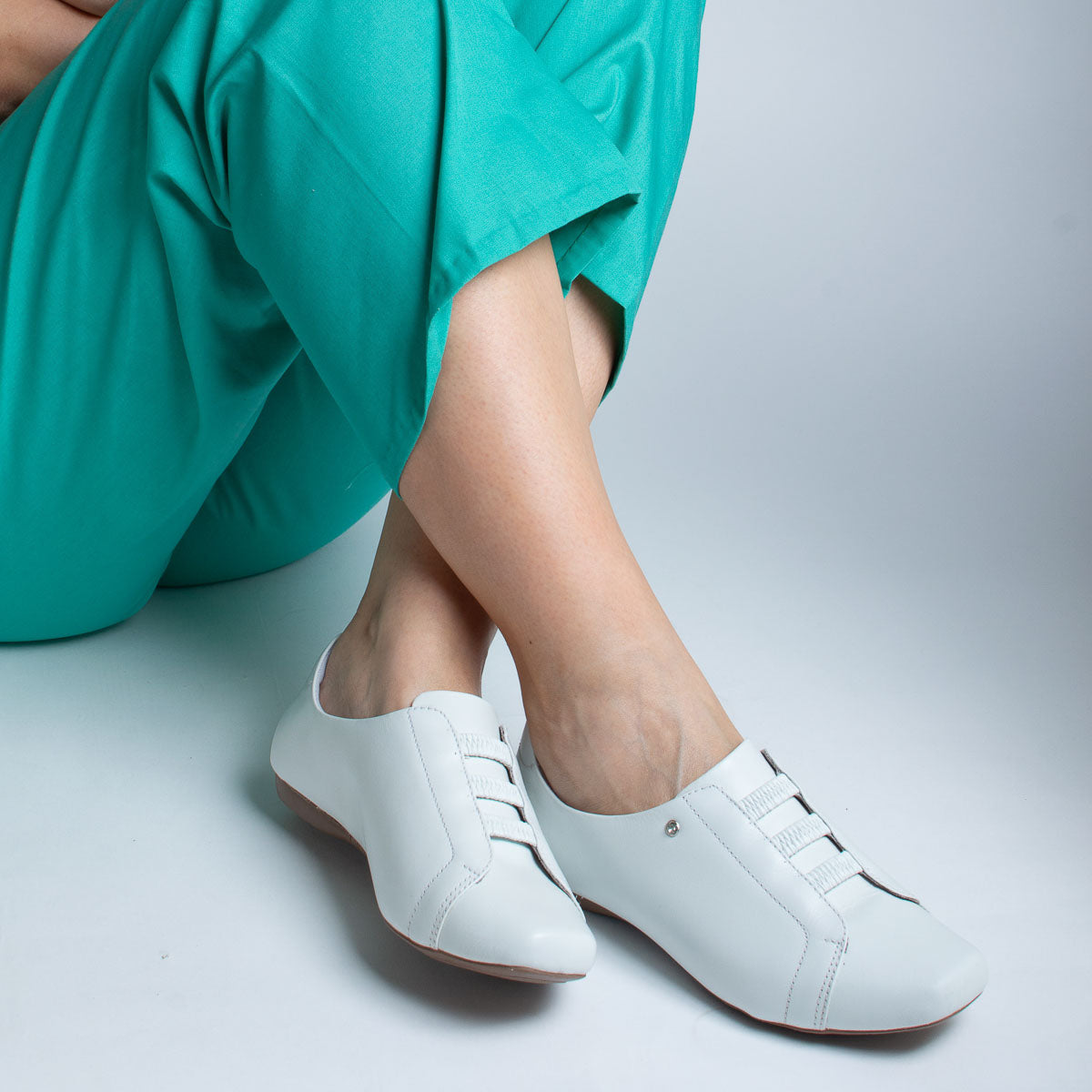 Woman wearing vegetal off-white Pau-Brasil shoes with teal scrubs - lifestyle view