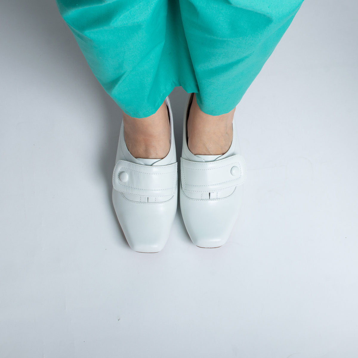 Woman wearing vegetal off-white Peroba shoes with teal scrubs - lifestyle view